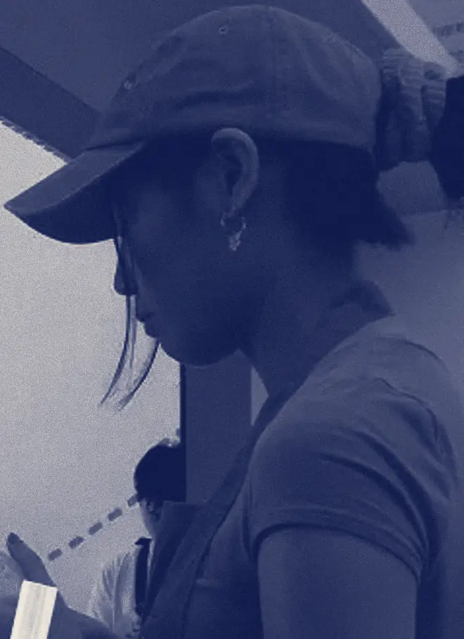 A woman in a cap and apron looks down at her work behind a tea shop counter.